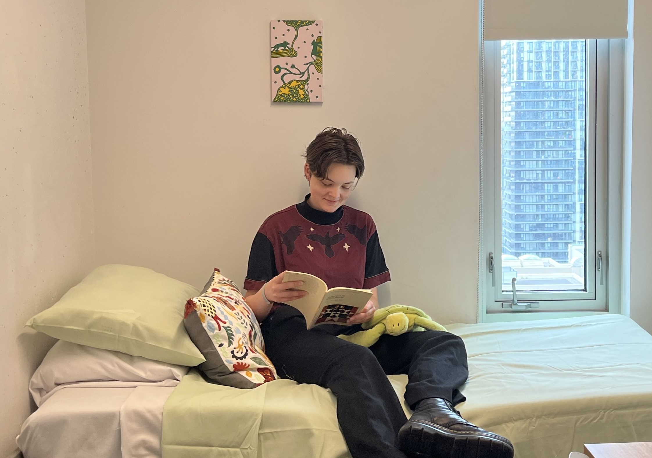 A student leans on desk in front of window in residence room